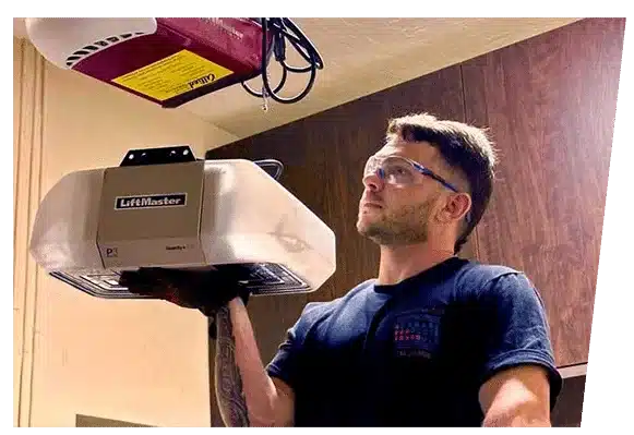 Technician wearing safety glasses installing a LiftMaster garage door opener.